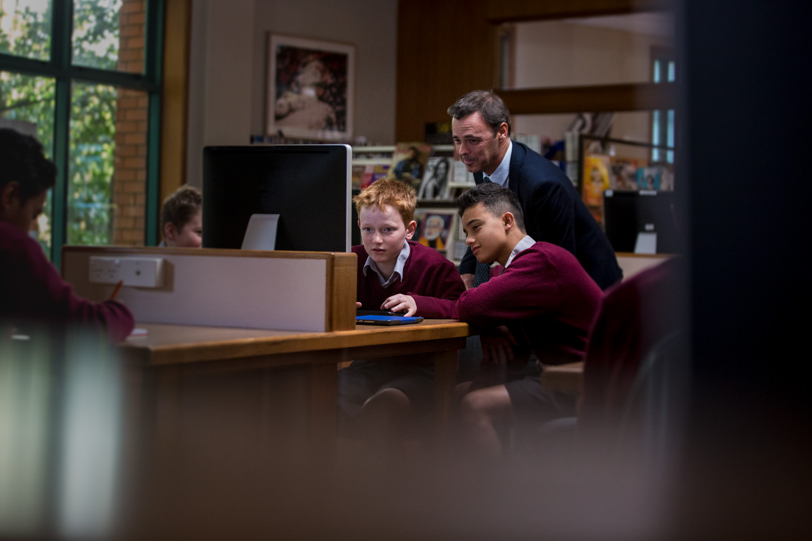 Year nine boys studying in the library supervised by a teacher 
